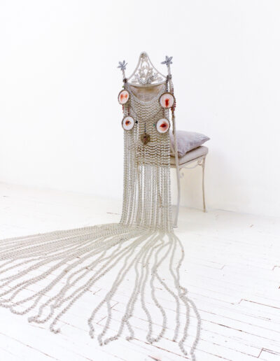 Esperanza Cortés; CHARMED LIFE; 2008 – 2012; Frescoes, chair, alabaster beads, glass beads, amulets, chains, brocade; 7’ L x 7’ W x 4’ H. The installation considers the physical/social/spiritual sacrifices made to conform. Bruises, lacerations, and contusions stand for the abuses imposed by self and others and question the lengths traversed to attain our desires and the desires themselves. What is exchange for life lived as a fairy tale?