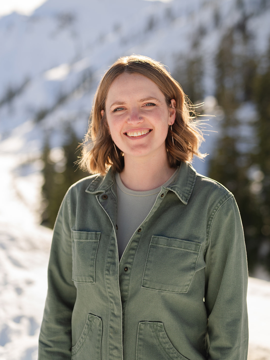 Woman with red-brown hair standing in front of a snowy landscape.