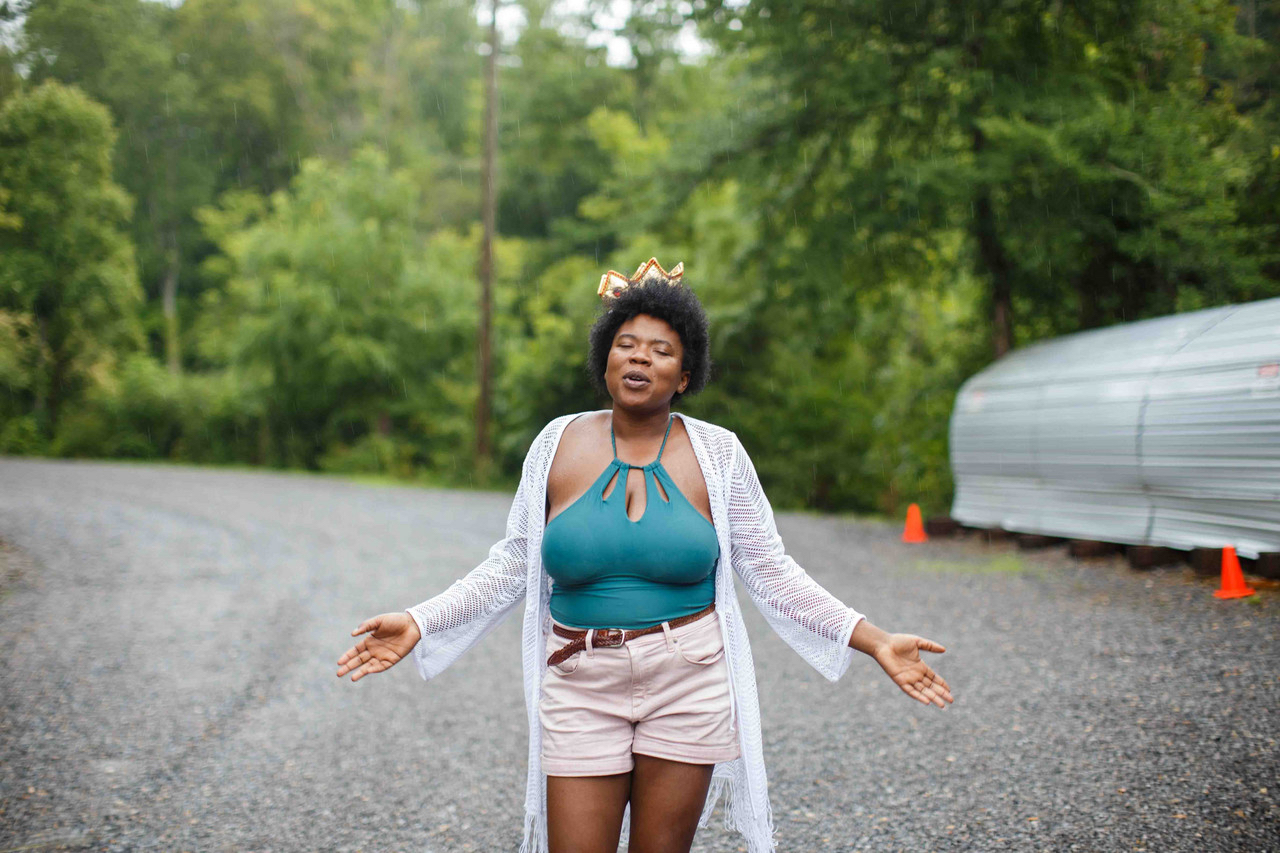 woman singing with arms outstretched in the middle of the road