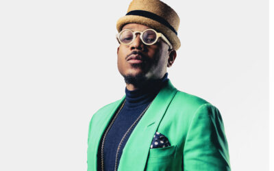 Man in green suit with round glasses and hat