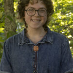 Turchin Center intern Emily Suit smiling wearing denim top and round glasses