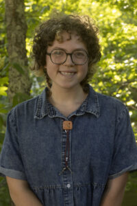 Turchin Center intern Emily Suit smiling wearing denim top and round glasses