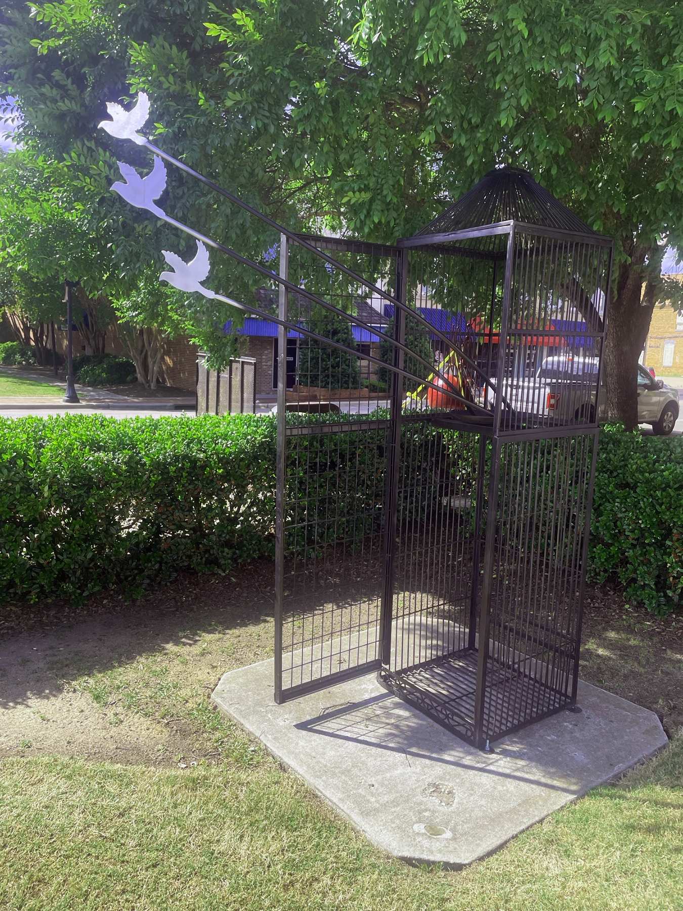 sculpture of open cage door with birds flying out
