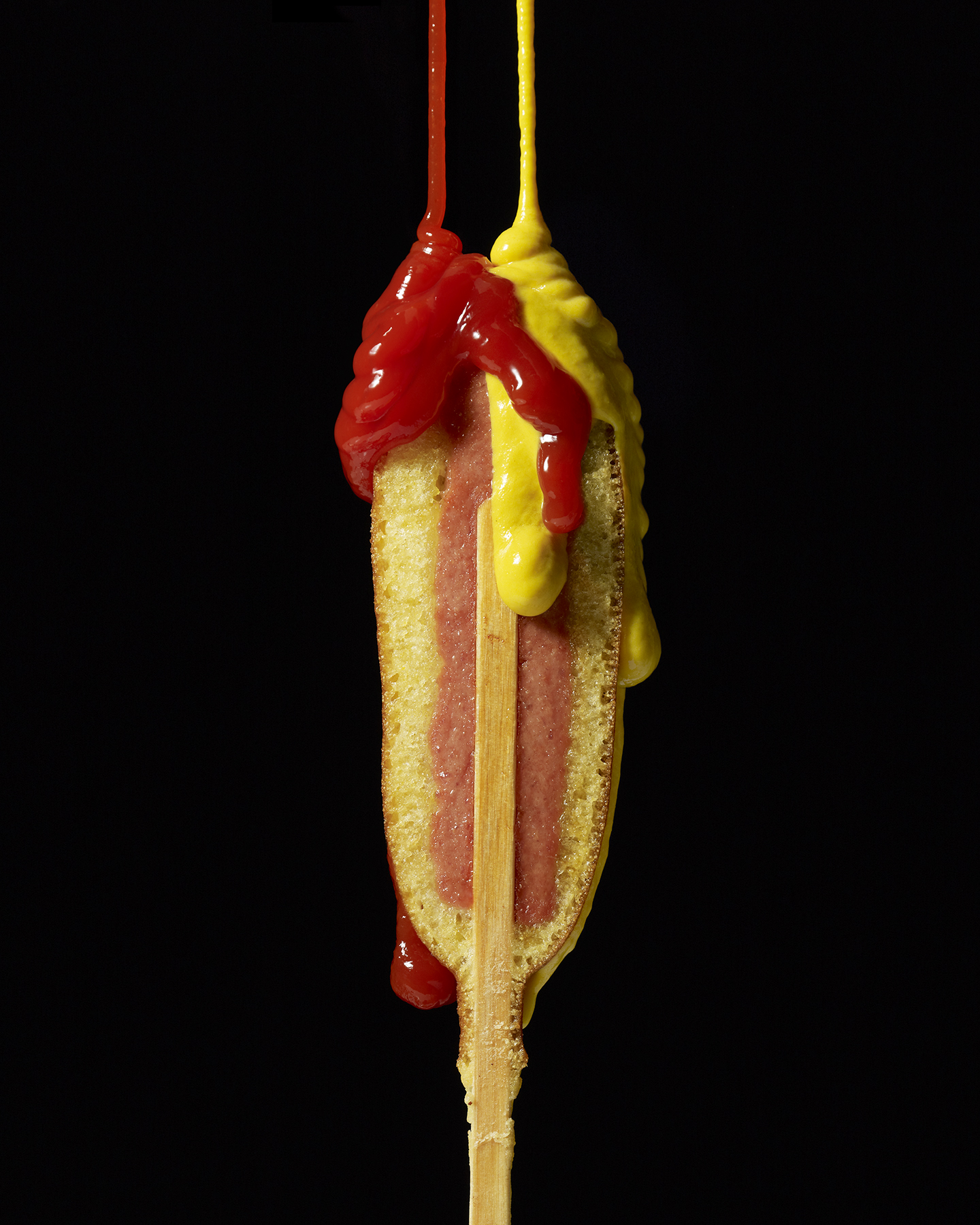 side view of corn dog with mustard and ketchup
