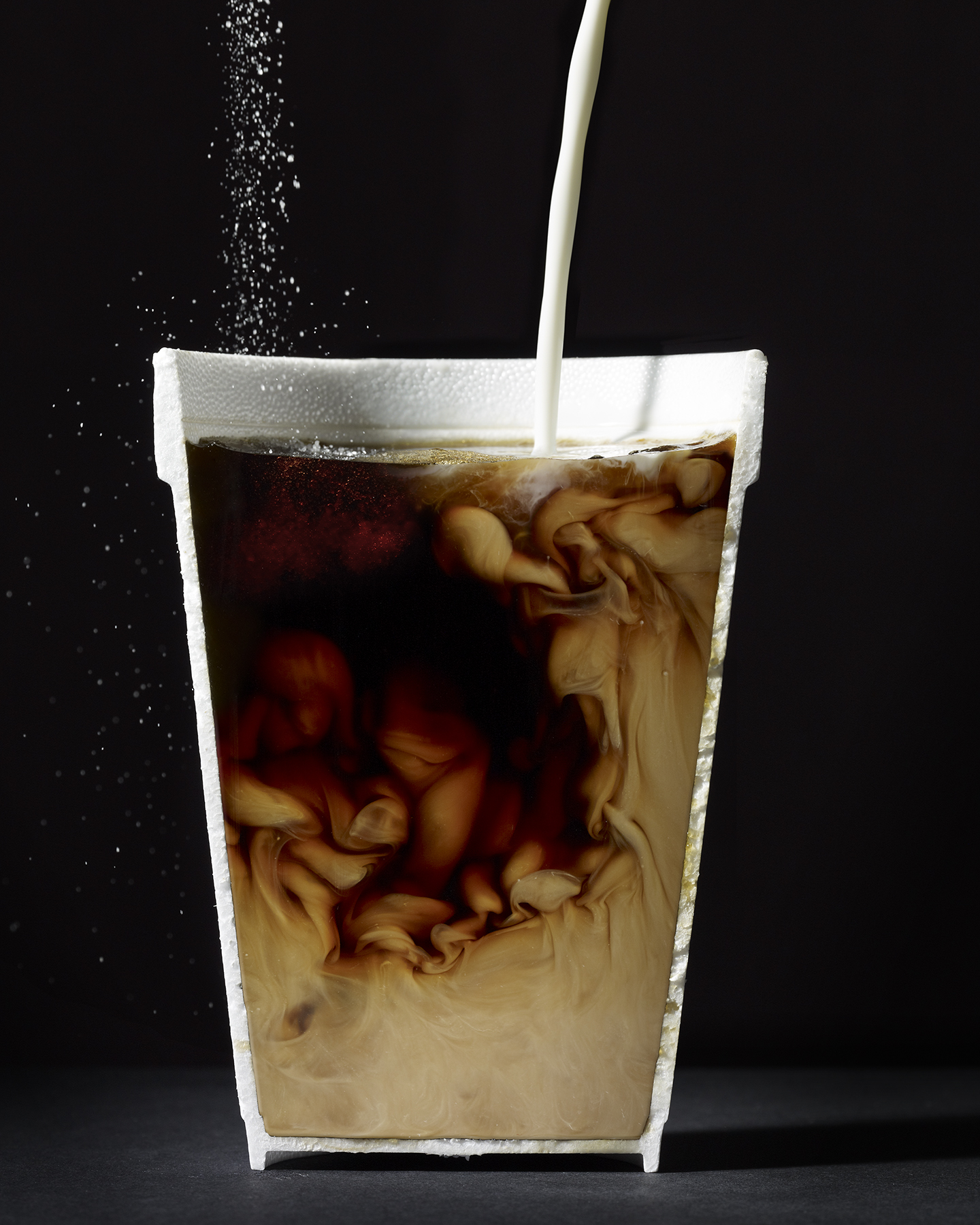 side view of coffee cup with milk and sugar splashing into syrofoam cup