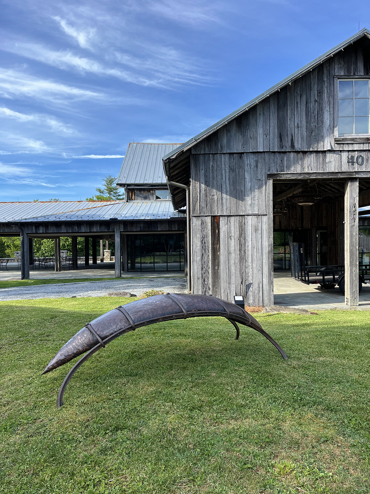 sculpture of copper bench in front of barn