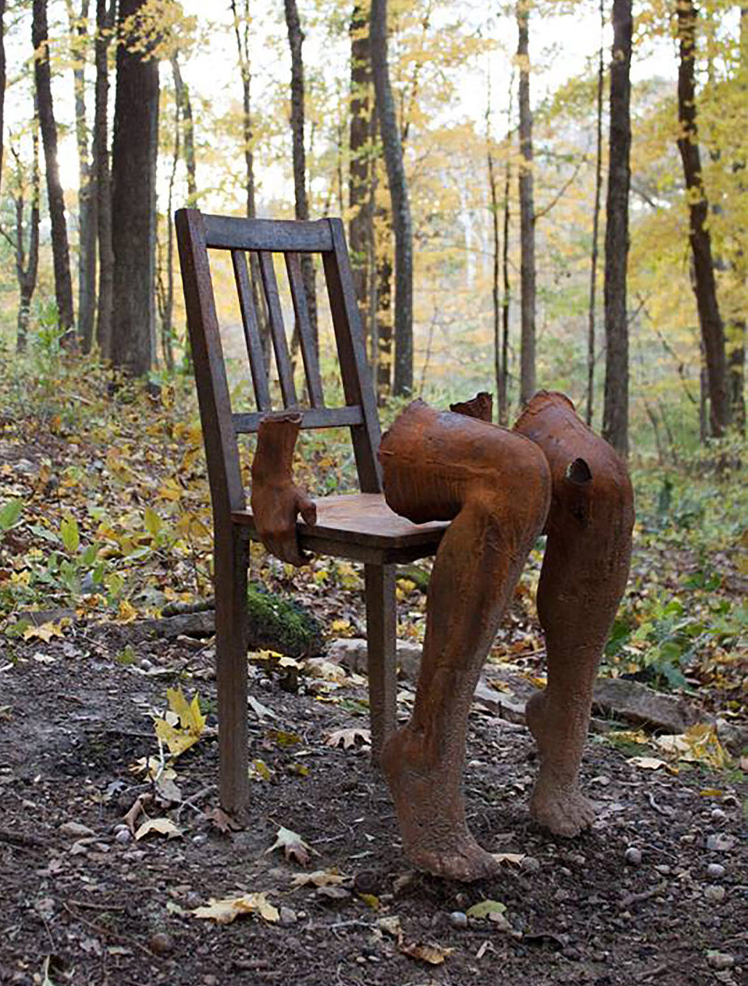 sculpture of legs on chair in a forest