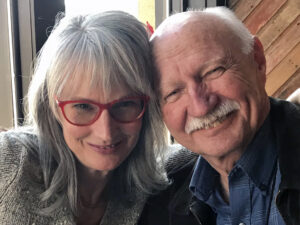 a woman in red glasses and a man smiling