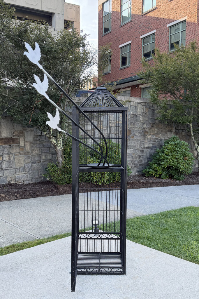 Sculpture resembling a bird cage with birds flying out