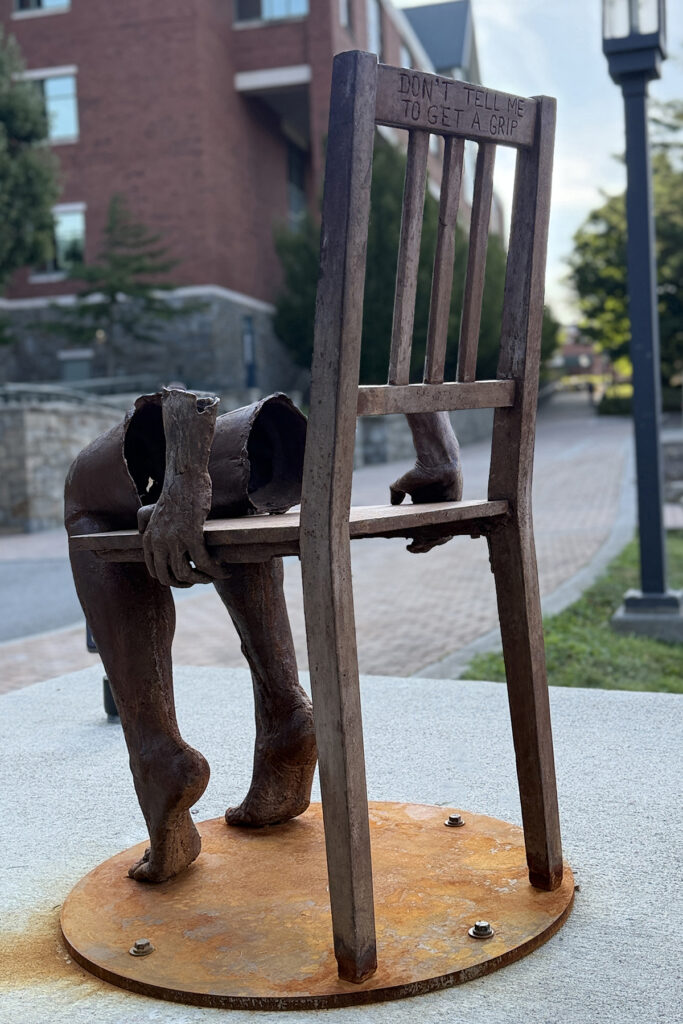 Sculpture of disembodied legs and hands on a chair