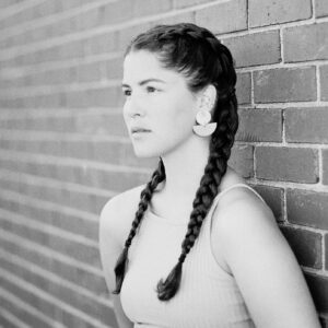 Woman with braided hair standing against a brick wall